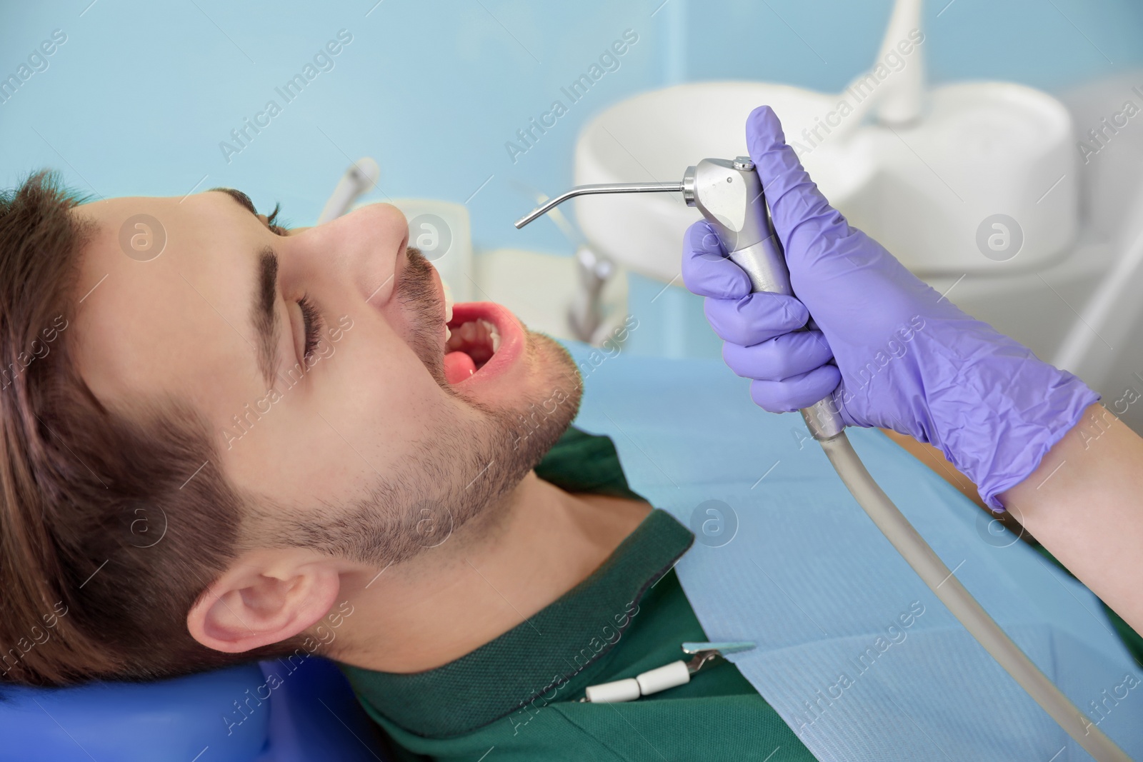 Photo of Professional dentist working with patient in modern clinic