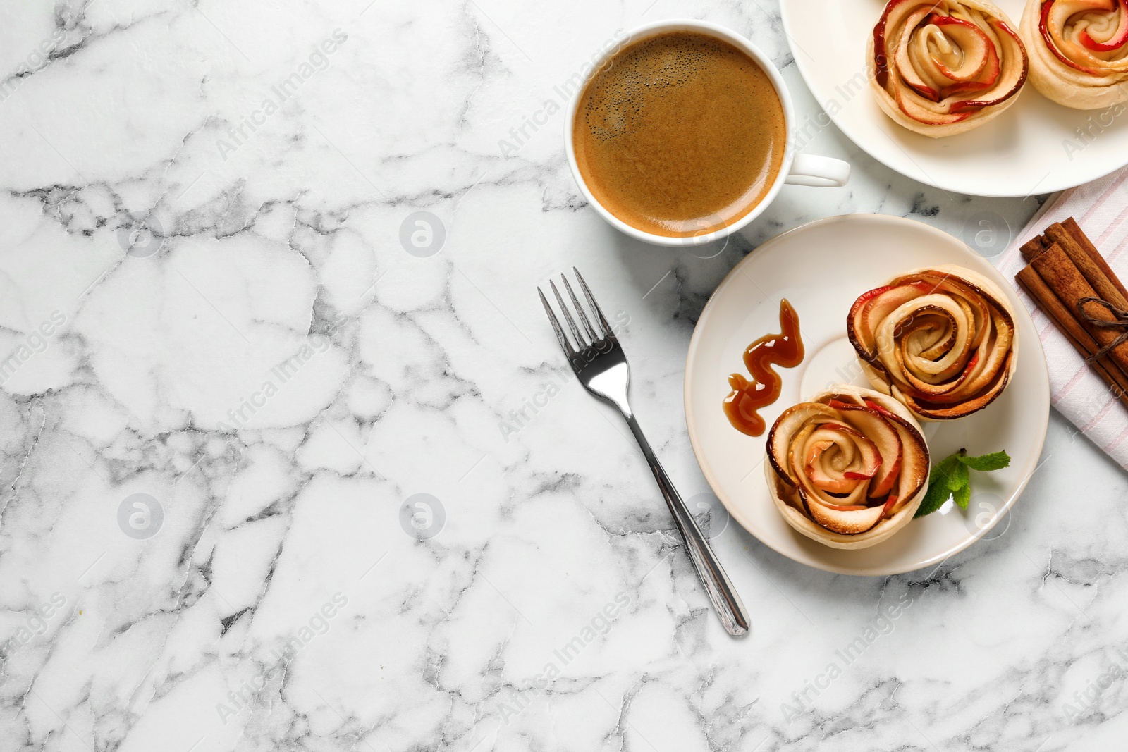 Photo of Freshly baked apple roses served on white marble table, flat lay. Space for text