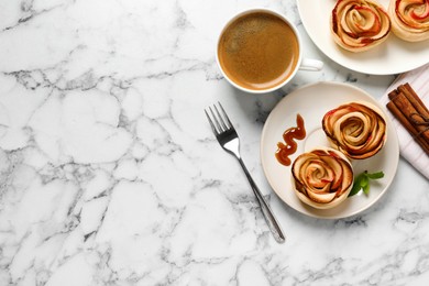 Photo of Freshly baked apple roses served on white marble table, flat lay. Space for text