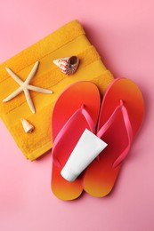 Sunscreen and beach accessories on pink background, flat lay