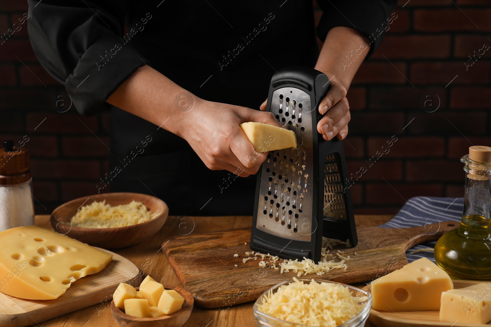 Photo of Woman grating cheese at wooden table, closeup