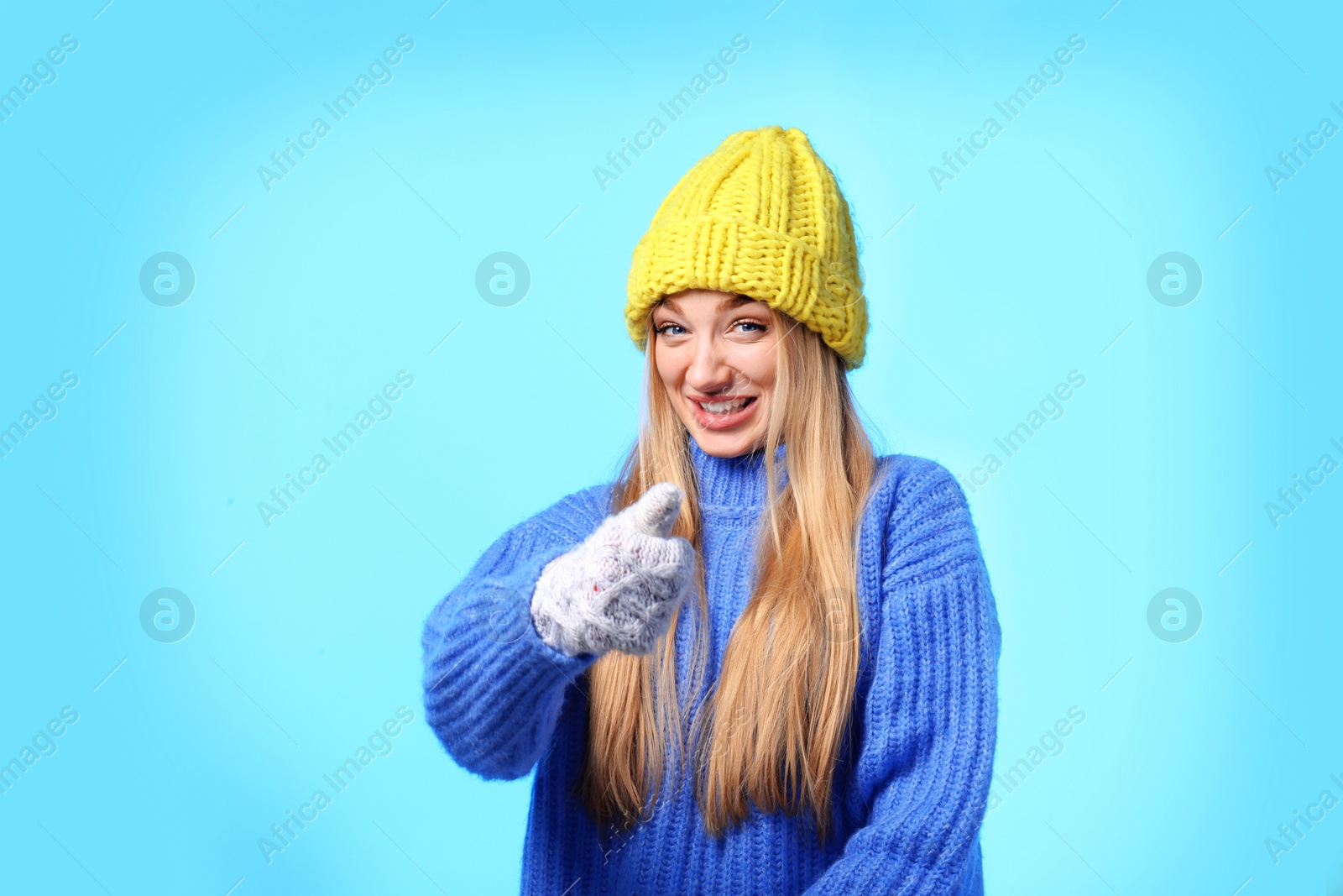 Photo of Portrait of emotional young woman in stylish hat, sweater and mittens on color background. Winter atmosphere