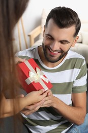 Man receiving gift from his girlfriend at home