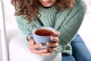 Photo of Woman with cup of hot tea indoors, closeup. Cozy home atmosphere