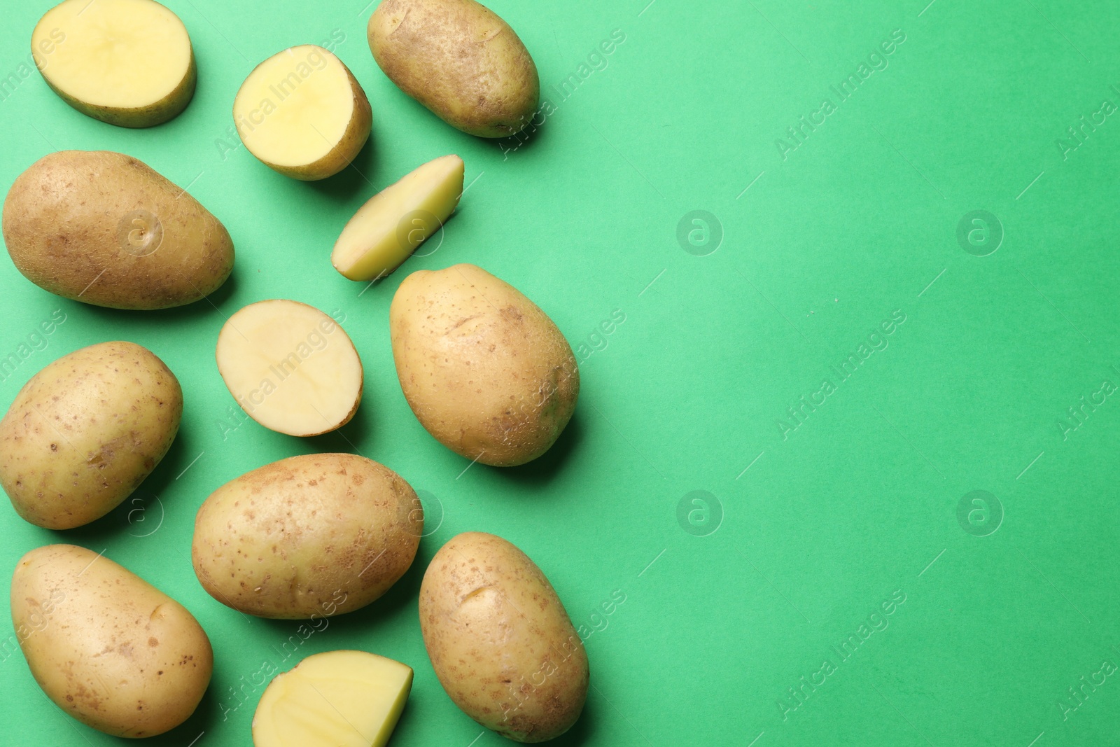 Photo of Fresh raw potatoes on green background, flat lay. Space for text