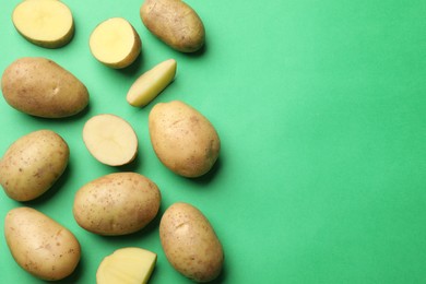 Photo of Fresh raw potatoes on green background, flat lay. Space for text