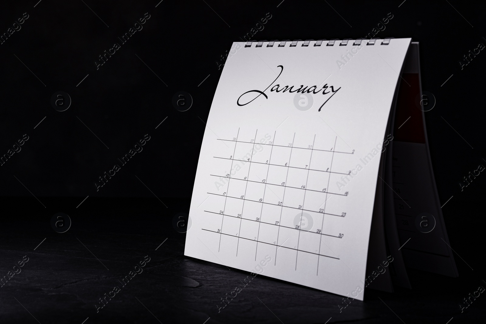 Photo of Paper calendar on black table, space for text. Planning concept