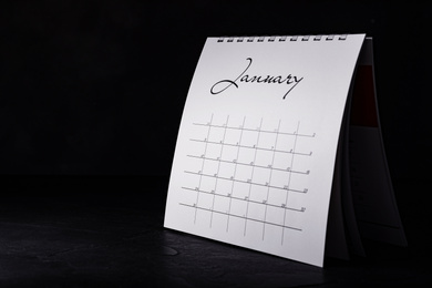 Paper calendar on black table, space for text. Planning concept