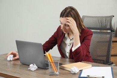 Sad businesswoman working at wooden table in office