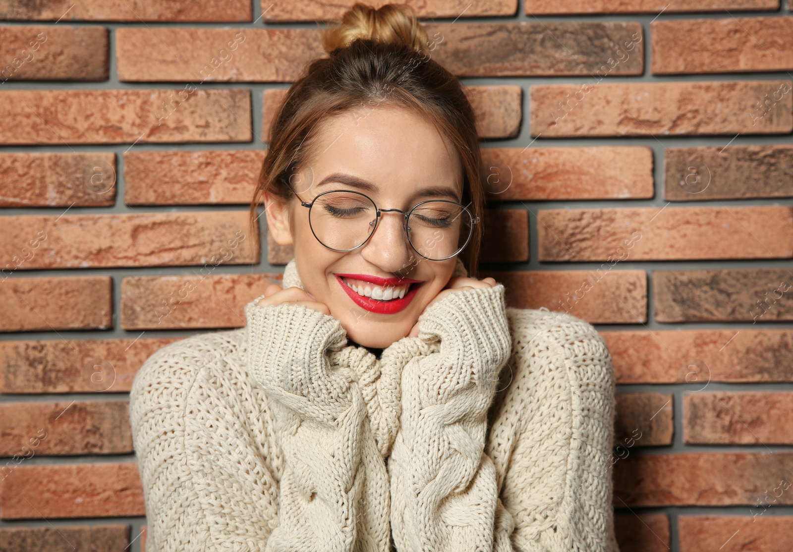 Photo of Beautiful young woman in warm sweater near brick wall