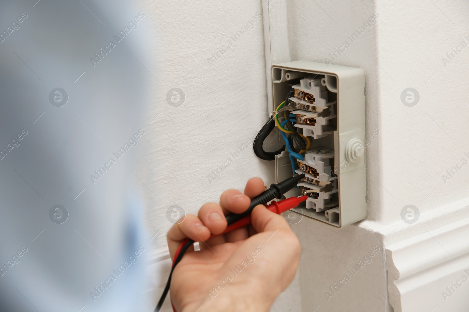 Photo of Electrician with tester checking voltage indoors, closeup