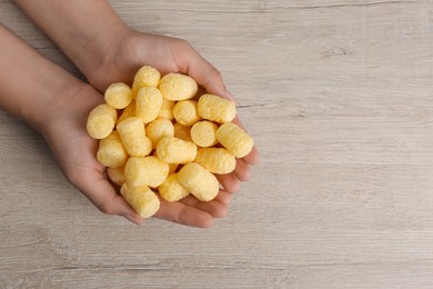 Woman holding corn sticks at wooden table, top view