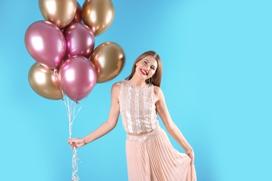 Young woman with air balloons on color background