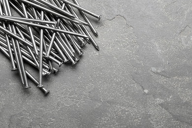 Photo of Pile of metal nails on grey stone background, flat lay. Space for text