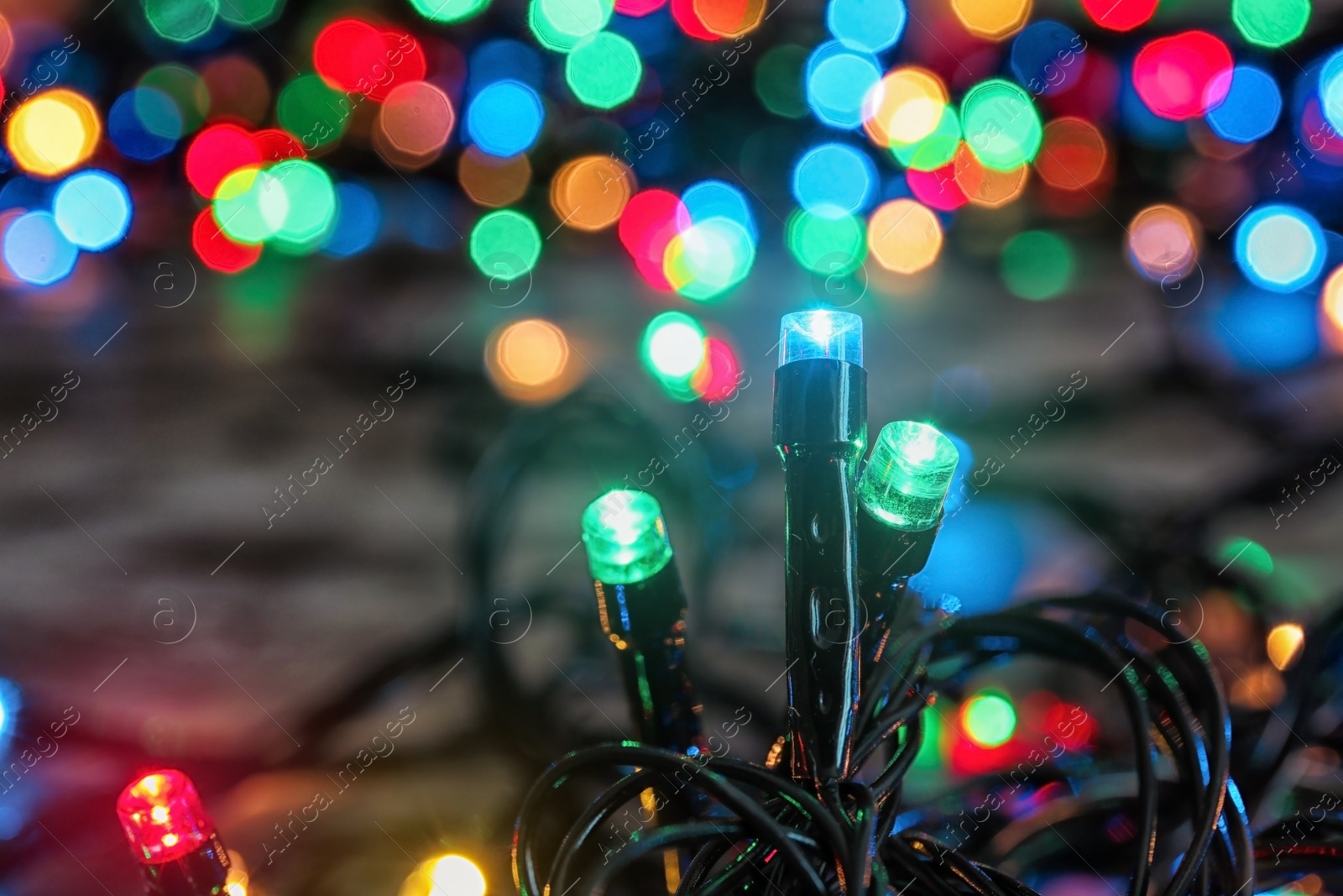 Photo of Beautiful bright Christmas lights on table, closeup