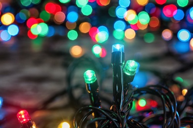 Photo of Beautiful bright Christmas lights on table, closeup