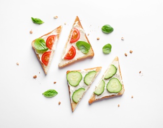 Photo of Tasty toast bread with cream cheese, cucumbers and cherry tomatoes on white background