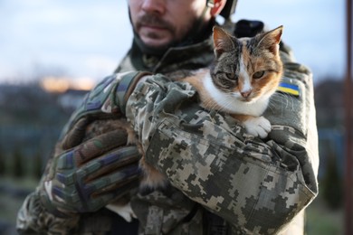 Photo of Ukrainian soldier with stray cat outdoors, closeup