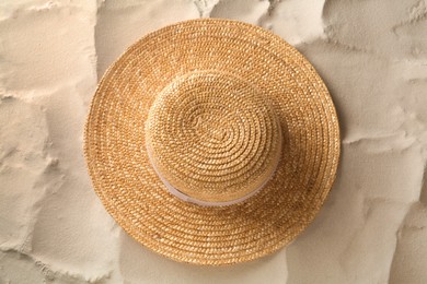 Stylish straw hat on sand, top view