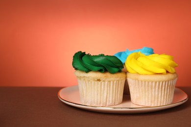 Delicious cupcakes with bright cream on color background, space for text