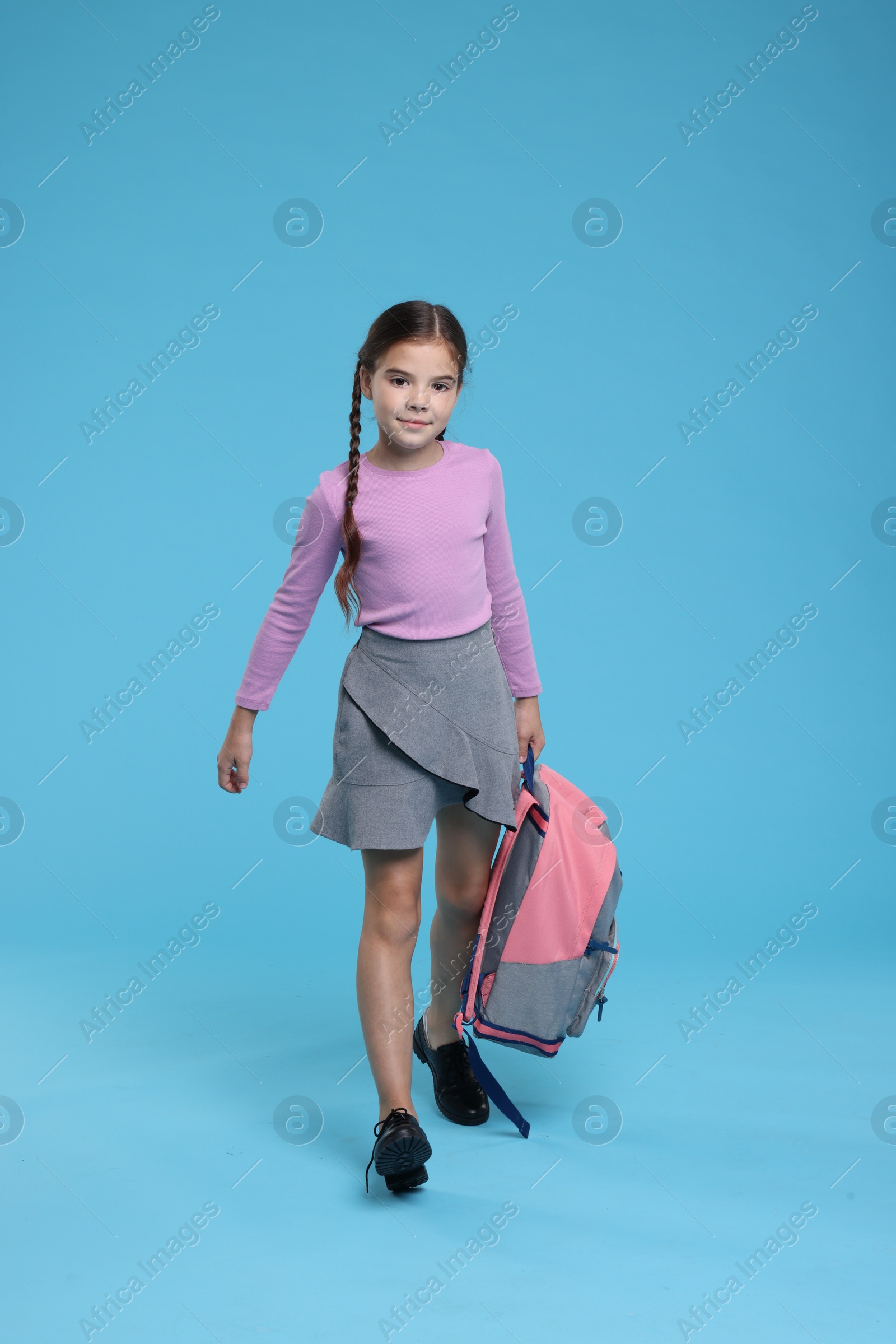 Photo of Back to school. Cute girl with backpack on light blue background