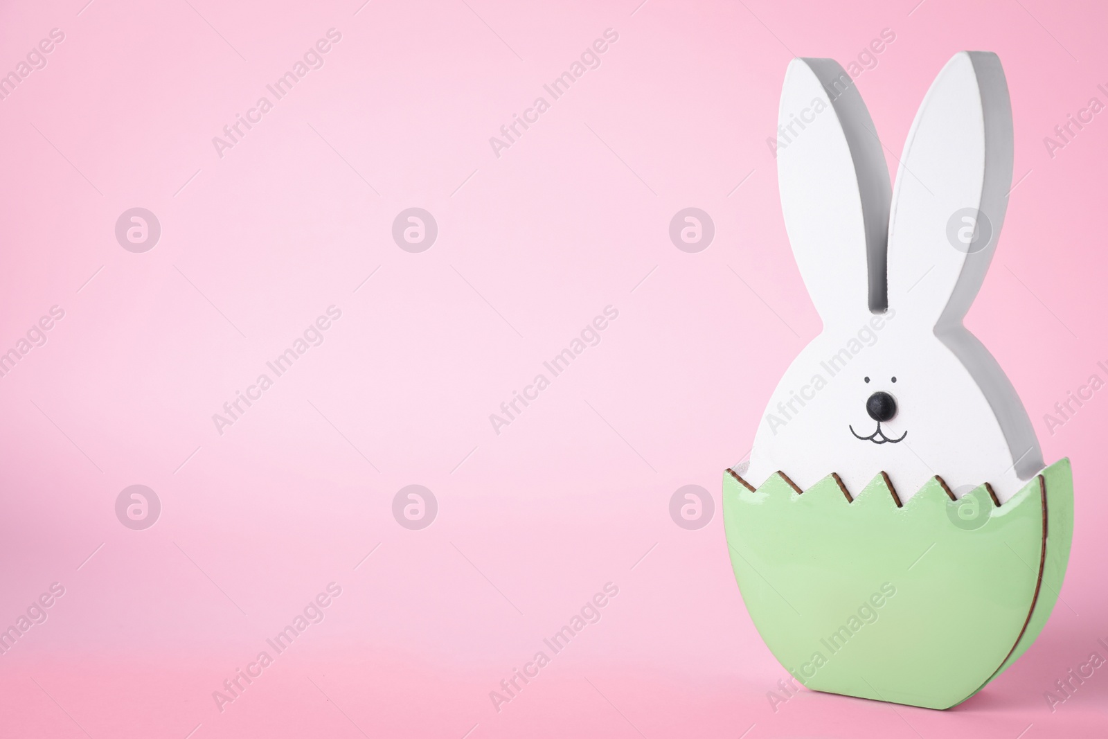 Photo of Easter bunny figure on pink background. Space for text