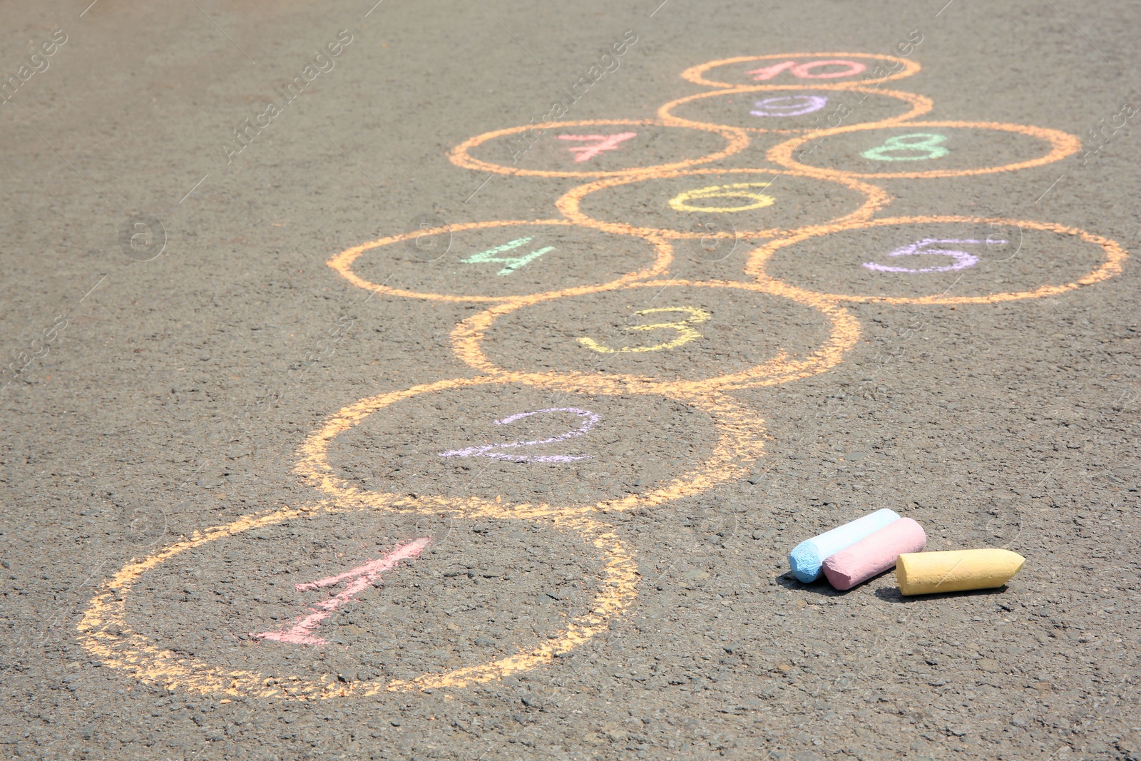 Photo of Hopscotch drawn with colorful chalk on asphalt outdoors, closeup