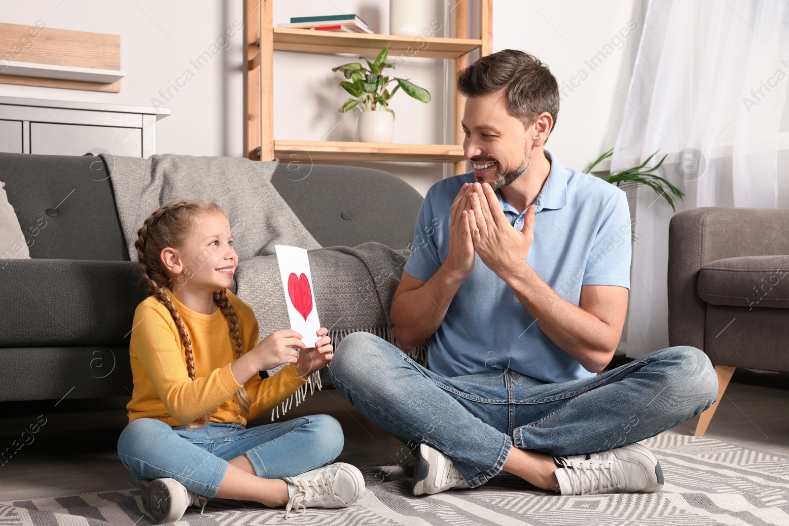 Photo of Happy man receiving greeting card from his little daughter at home