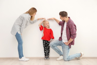 Parents measuring their daughter's height indoors