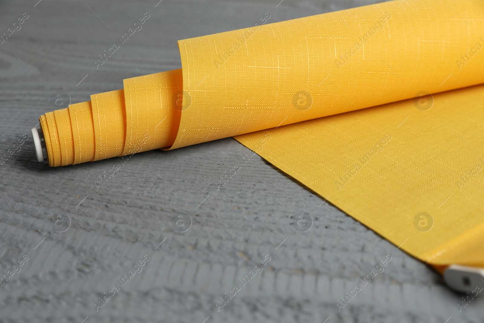 Photo of Stylish roller window blinds on grey wooden table