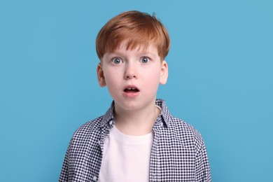 Surprised little boy on light blue background