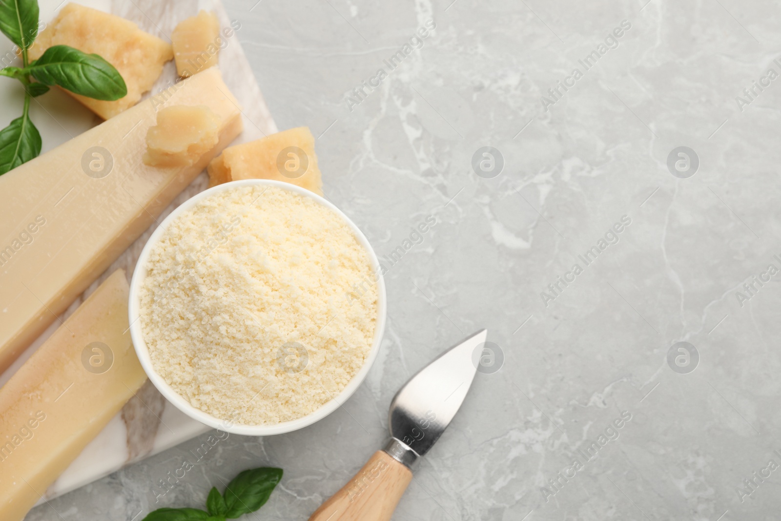 Photo of Flat lay composition with parmesan cheese, basil and knife on grey table. Space for text