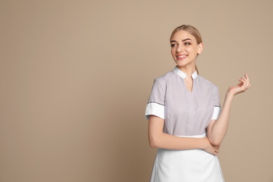 Photo of Portrait of young chambermaid in tidy uniform on color background