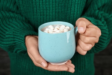 Photo of Woman holding cup of delicious hot cocoa drink with marshmallows, closeup