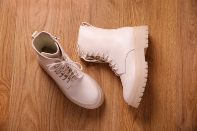 Pair of stylish beige leather shoes on wooden floor, top view