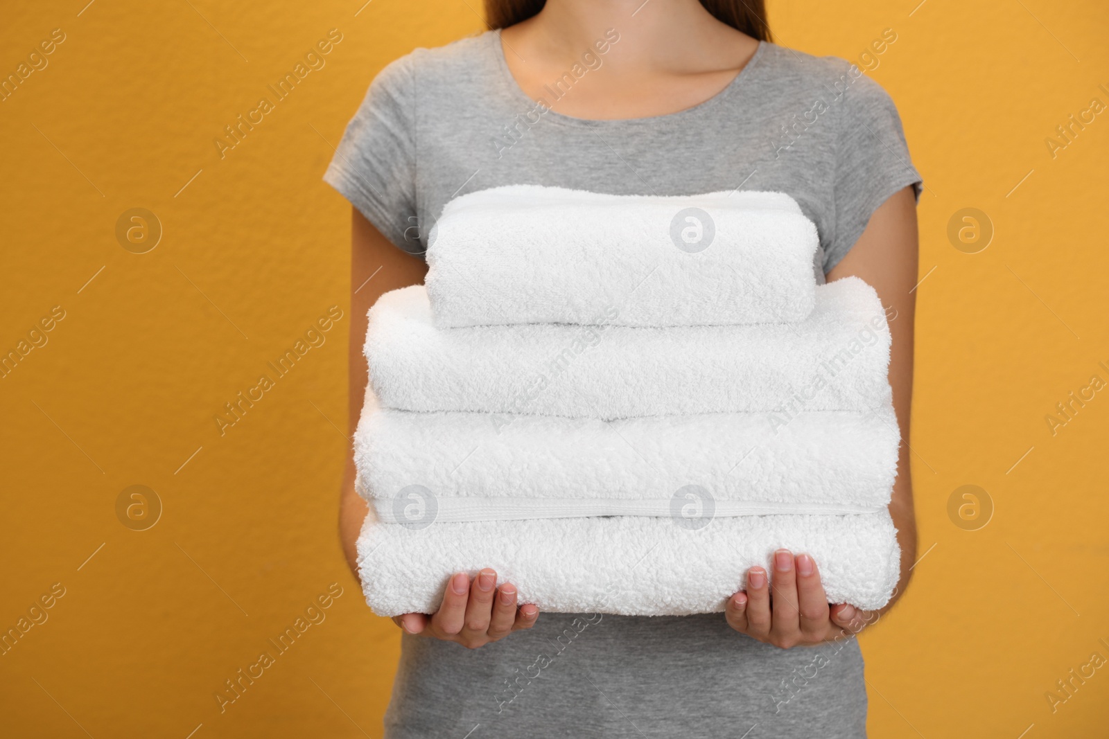 Photo of Woman holding fresh towels on orange background, closeup