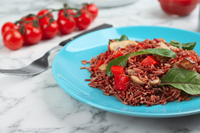 Photo of Tasty brown rice with vegetables on white marble table, closeup