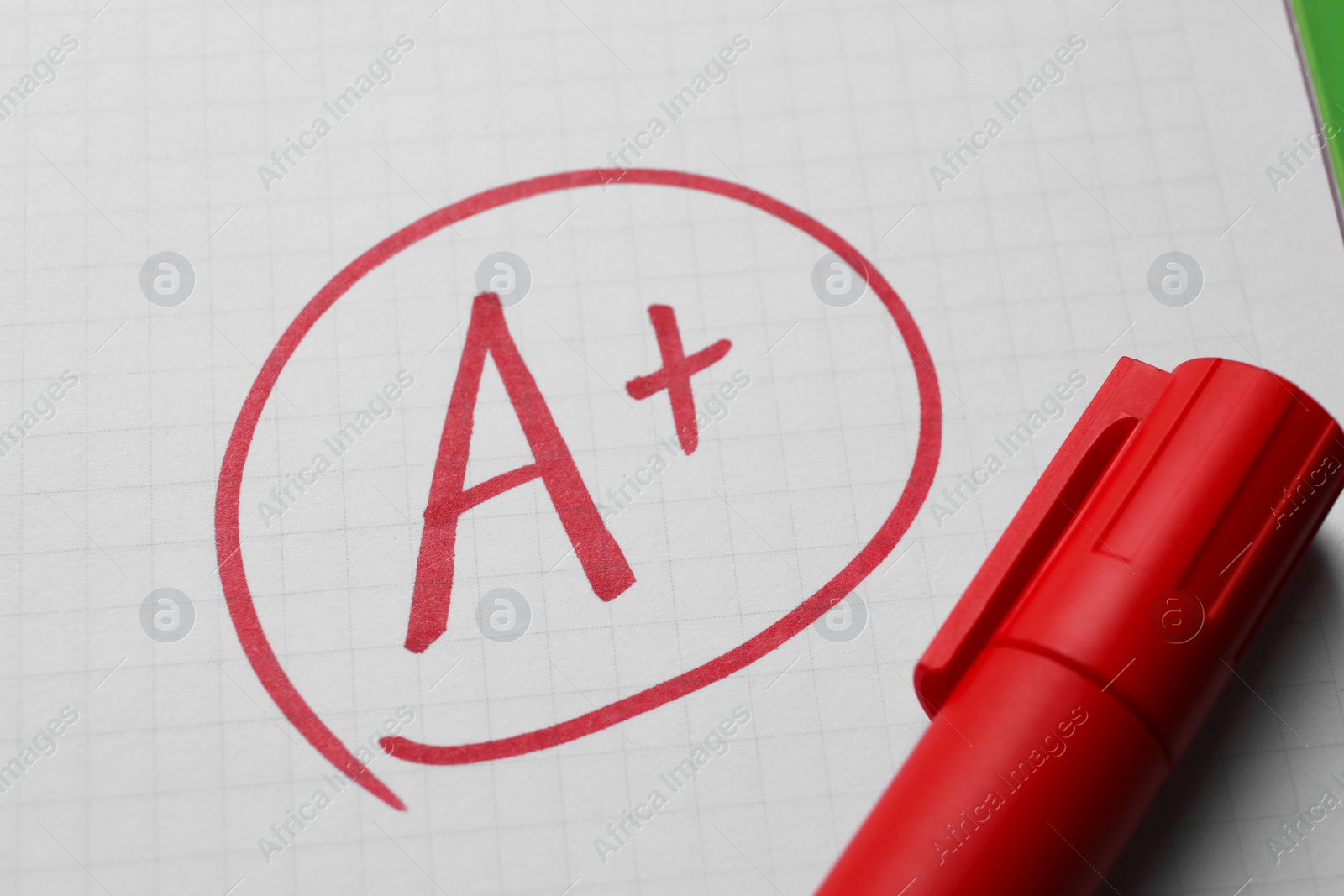 Photo of School grade. Red letter A with plus symbol on notebook paper and marker, closeup