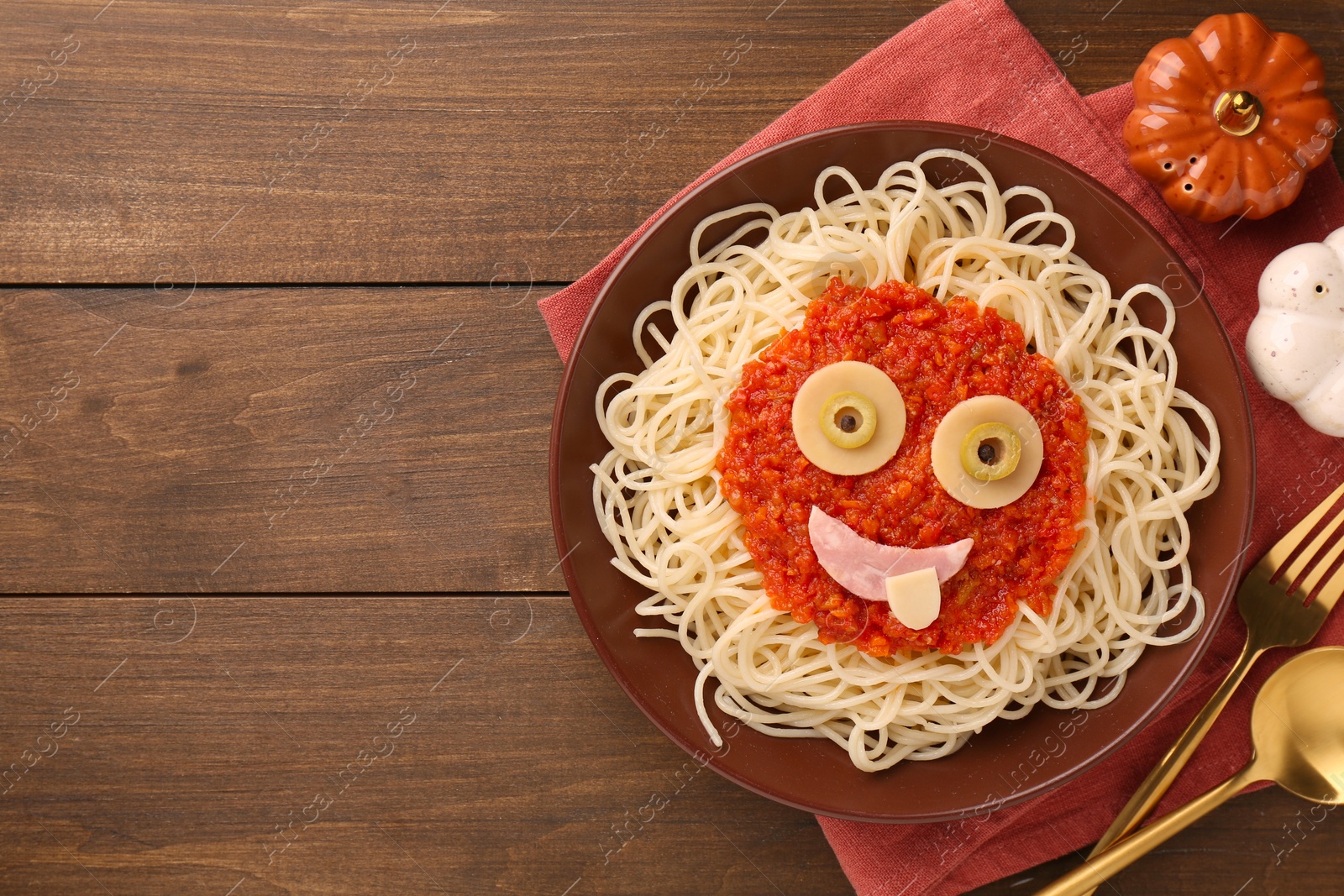 Photo of Plate with funny monster made of tasty pasta served on wooden table, flat lay with space for text. Halloween food