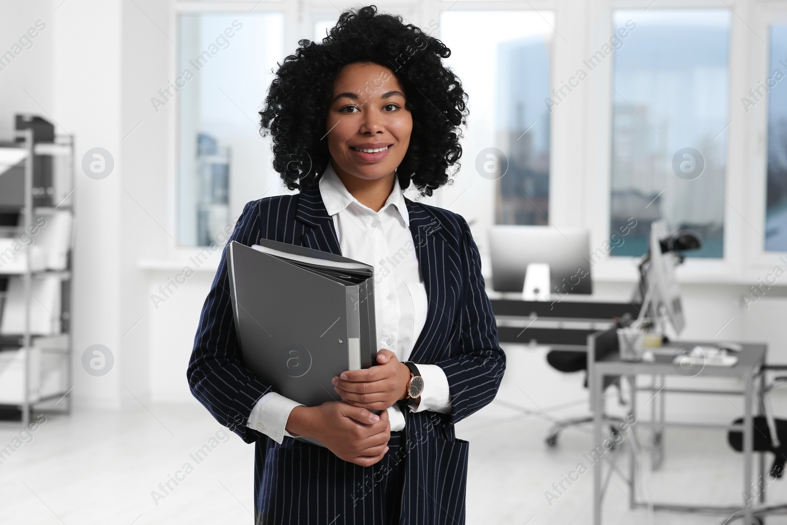 Photo of Smiling young businesswoman with folders in office