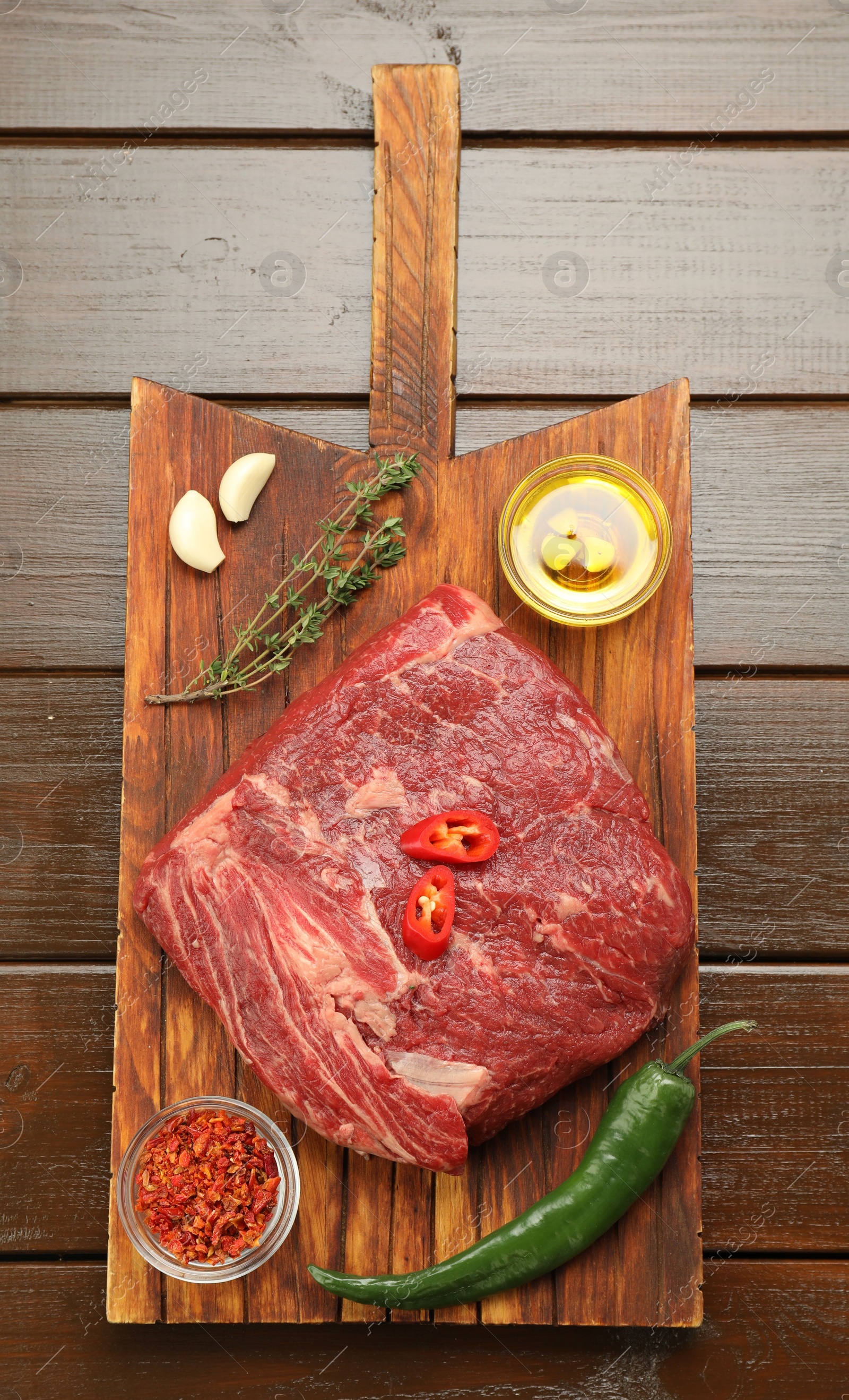 Photo of Fresh raw beef cut, spices and oil on wooden table, top view