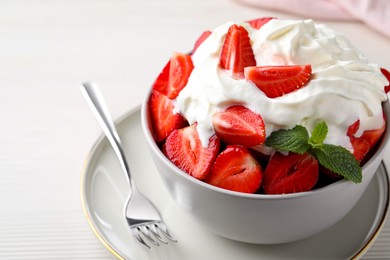 Photo of Delicious strawberries with whipped cream served on white wooden table, closeup