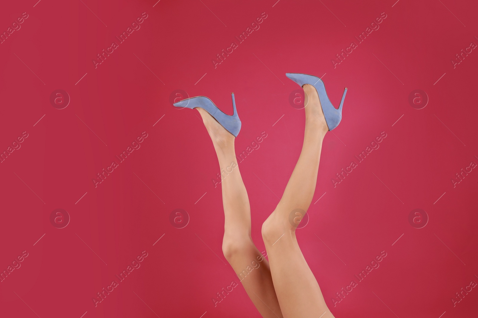 Photo of Woman in elegant shoes on crimson background