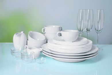 Set of clean dishes and glasses on light blue table