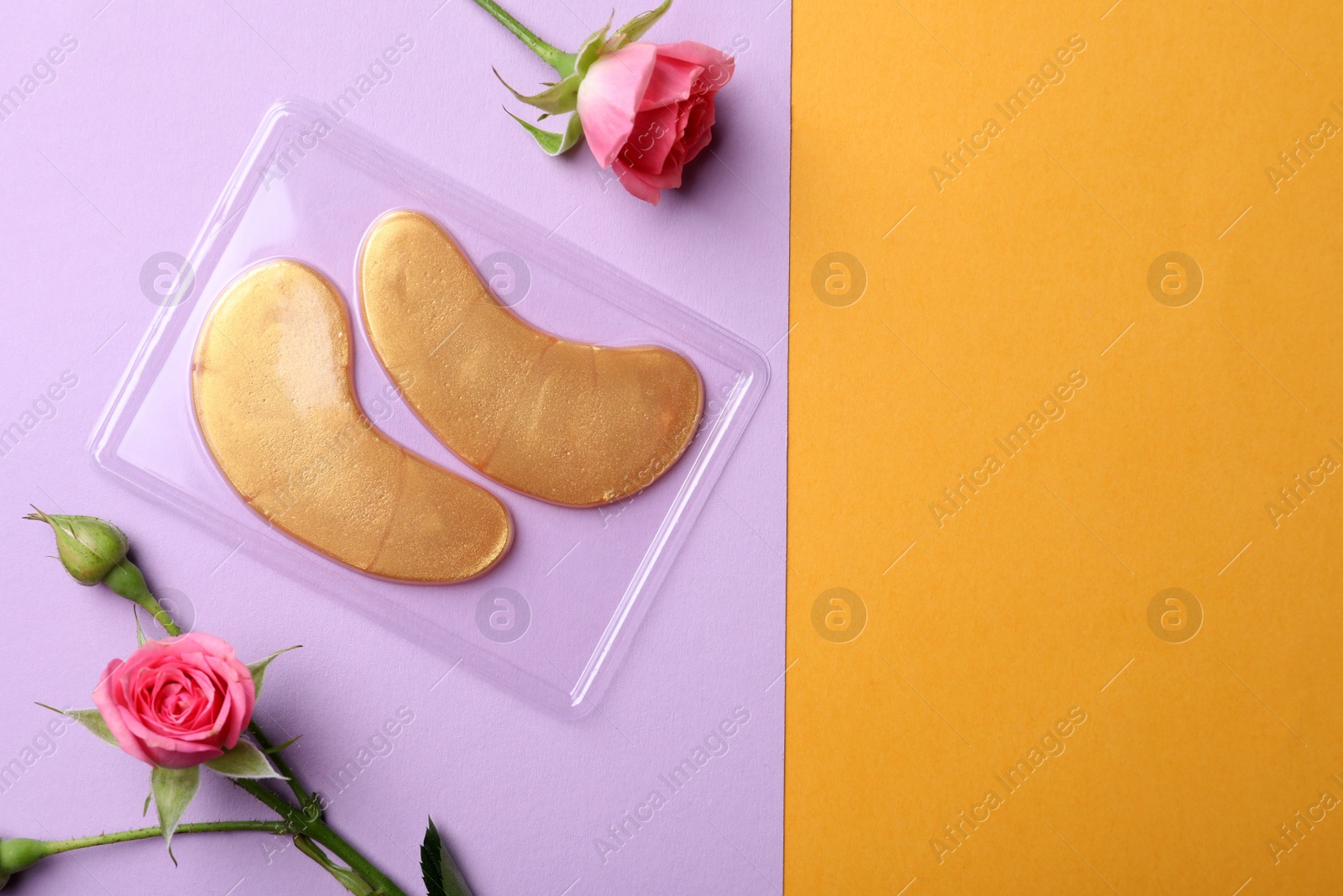 Photo of Under eye patches and rose flowers on color background, flat lay with space for text. Cosmetic product