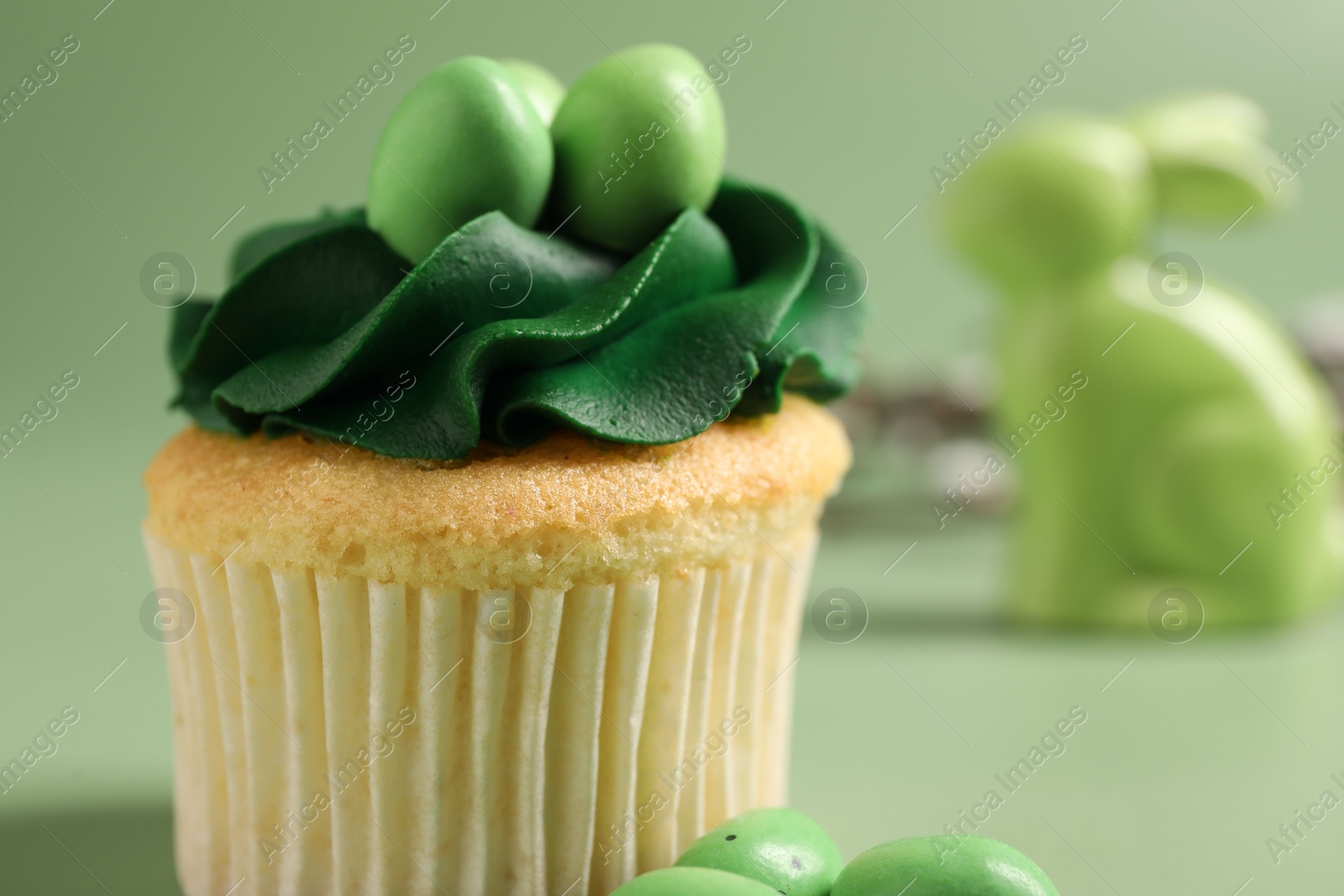 Photo of Tasty decorated Easter cupcake on green background, closeup