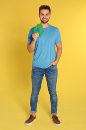 Young man with recycling symbol on yellow background