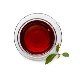 Photo of Glass cup of hot aromatic tea and green leaves on white background, top view
