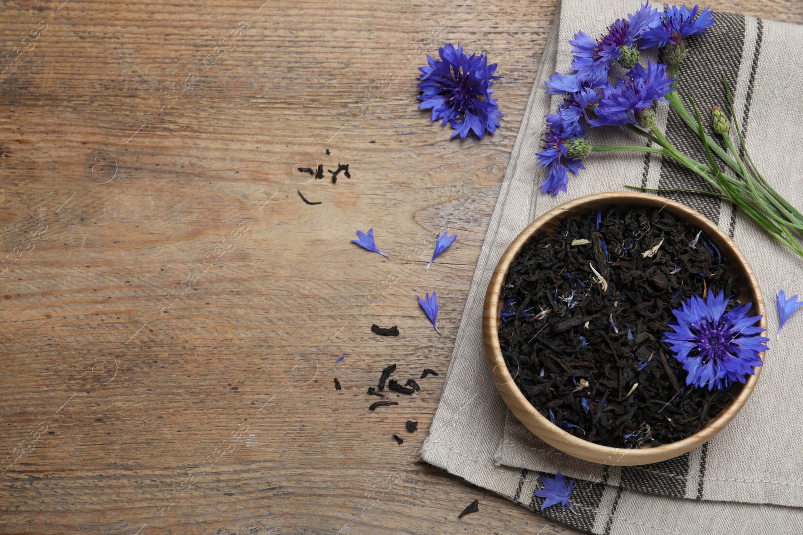 Photo of Dried cornflower tea and fresh flowers on wooden table, flat lay. Space for text