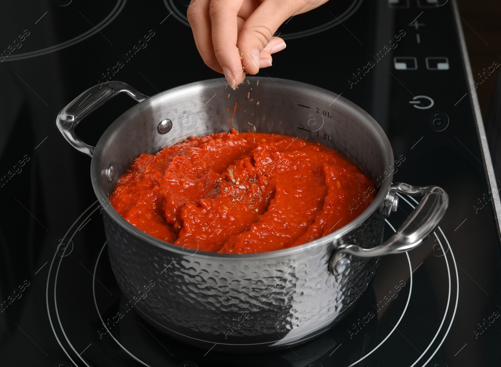 Photo of Woman cooking delicious tomato sauce in pan on stove, closeup